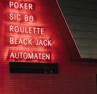 Red neon letters are mounted on a dark tiled wall, displaying the words Poker, Sic Bo, Roulette, Black Jack, and Automaten.