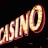 Brightly illuminated letters spell out 'CASINO' with glowing yellow bulbs and red outlines against a dark background.